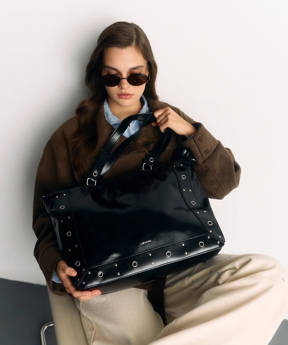 Bolso Notebook Charol Eyelets de Lounge, negro, con eyelets y detalles metálicos, modelo femenino.