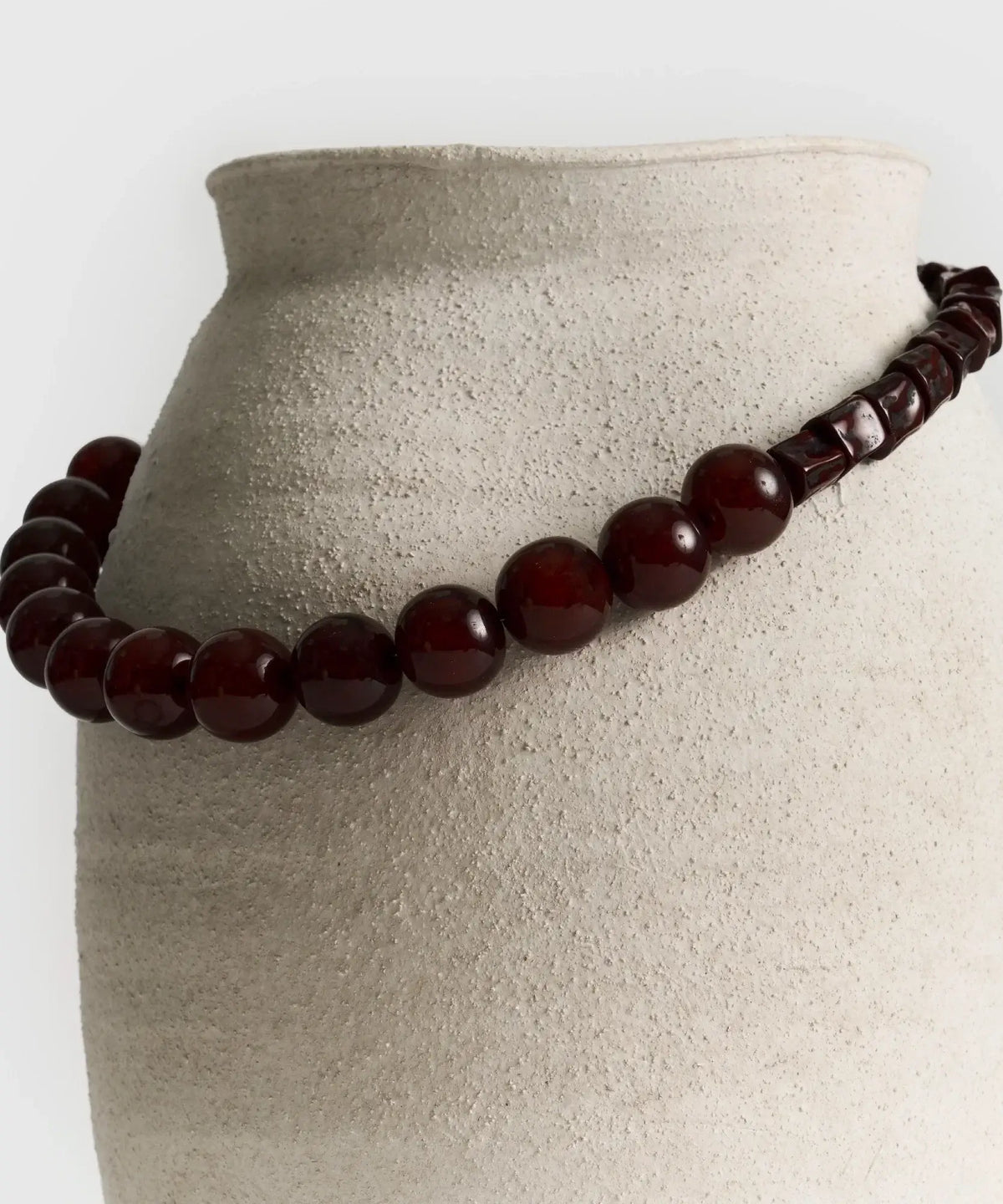 Collar Piedras Combinadas de Lounge con piedras de resina en tonos café sobre jarrón blanco.
