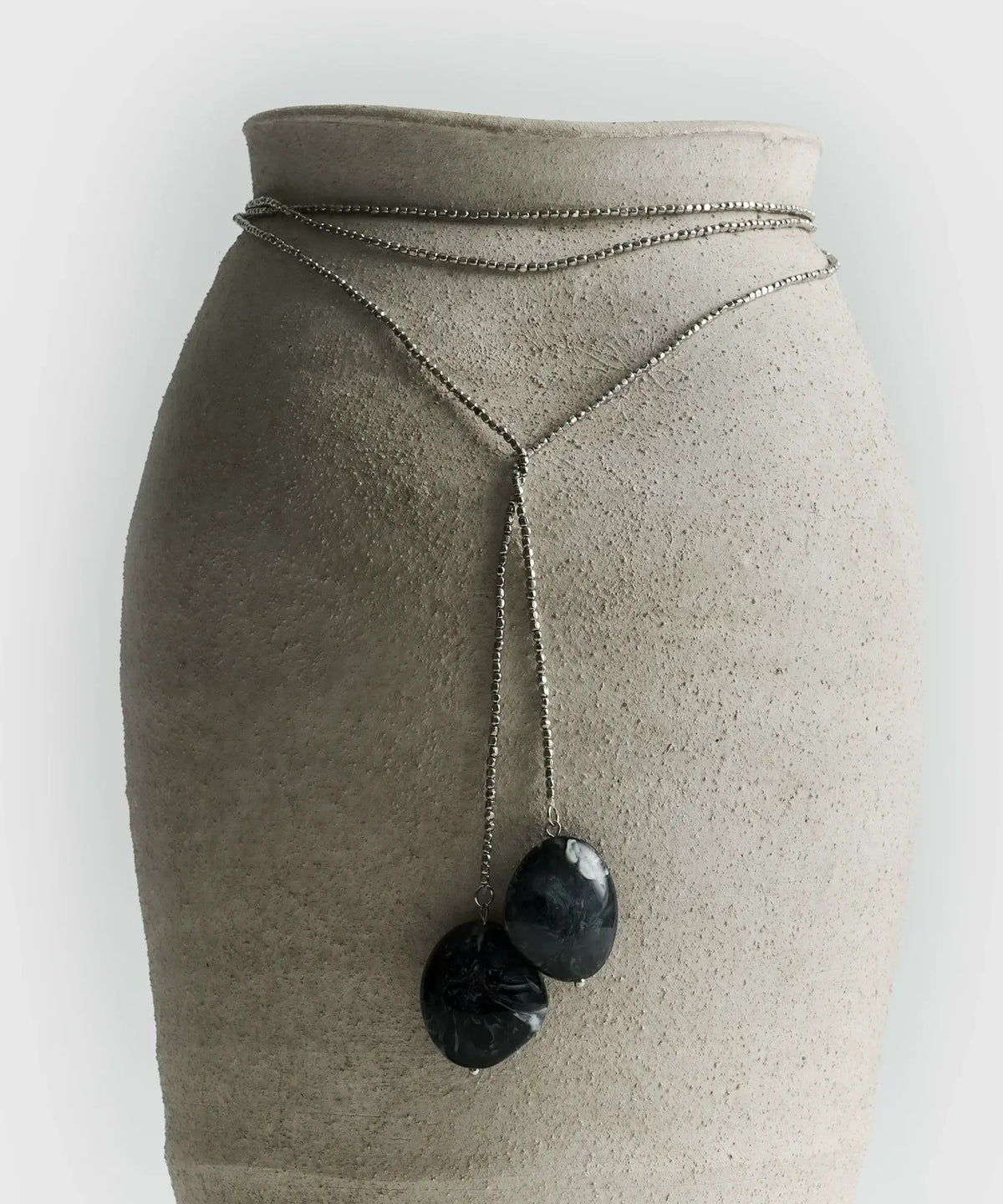Collar Envolvente largo con mostacillas y piedras de resina, presentado sobre un soporte elegante.