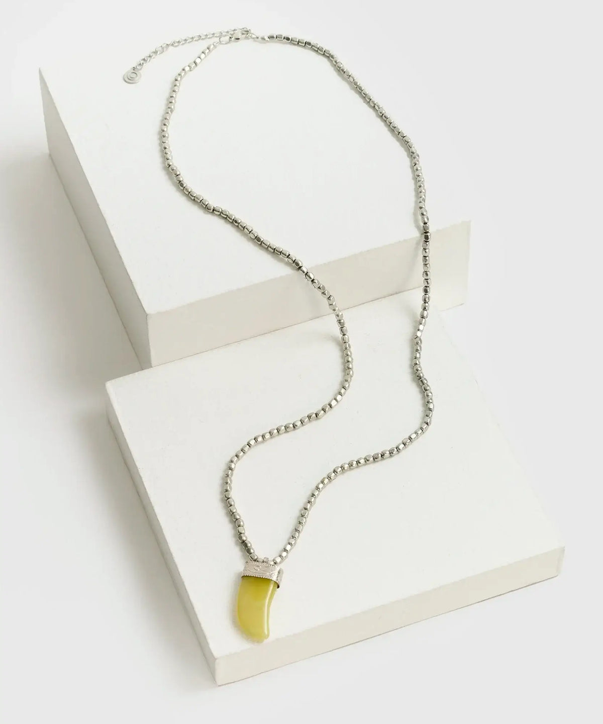 Collar Mostacillas Boho de Lounge con charm en forma de colmillo sobre fondo blanco.