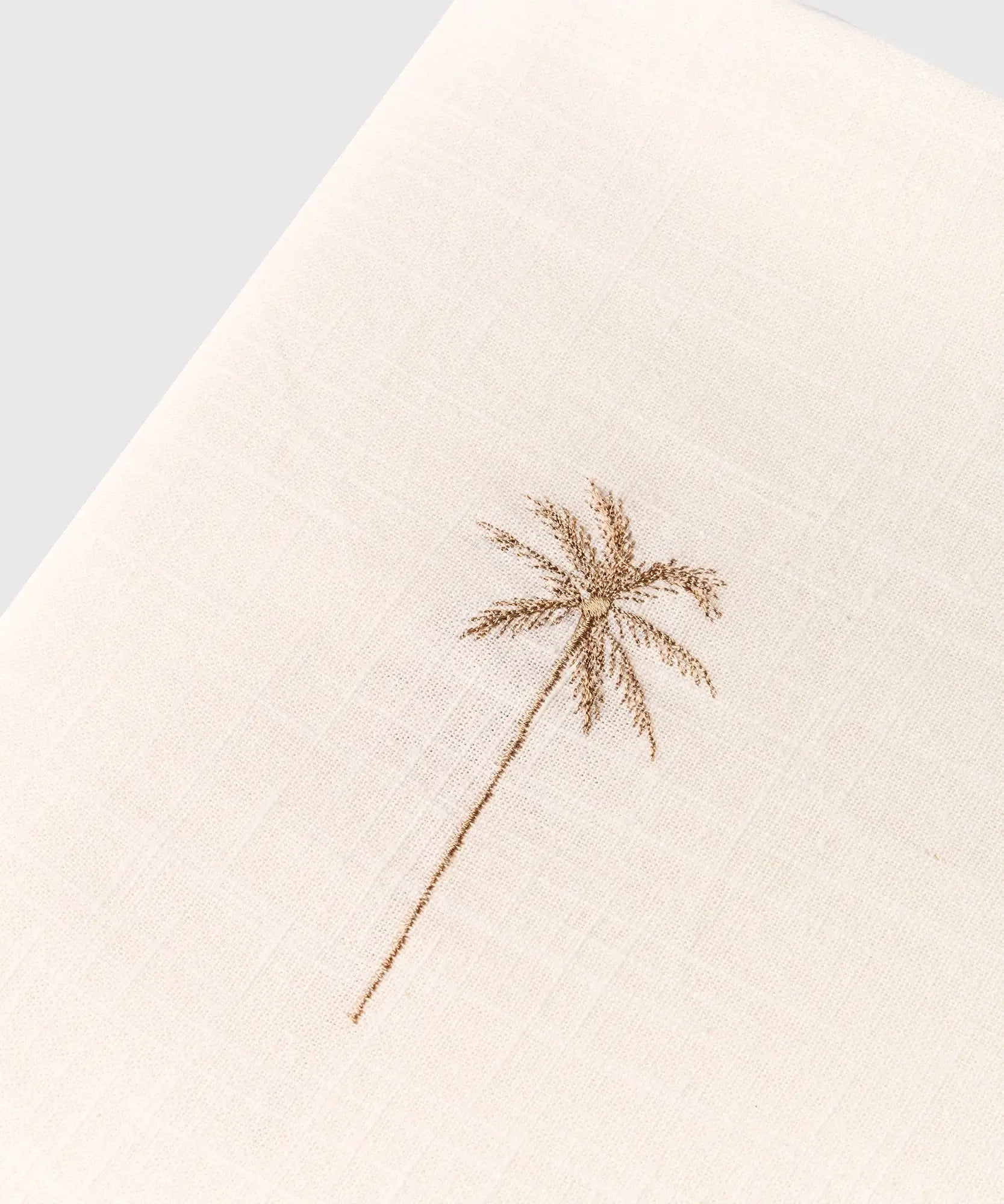 Mantel Palmeras Bordadas con diseño elegante de palmera bordada en tono beige sobre fondo blanco.