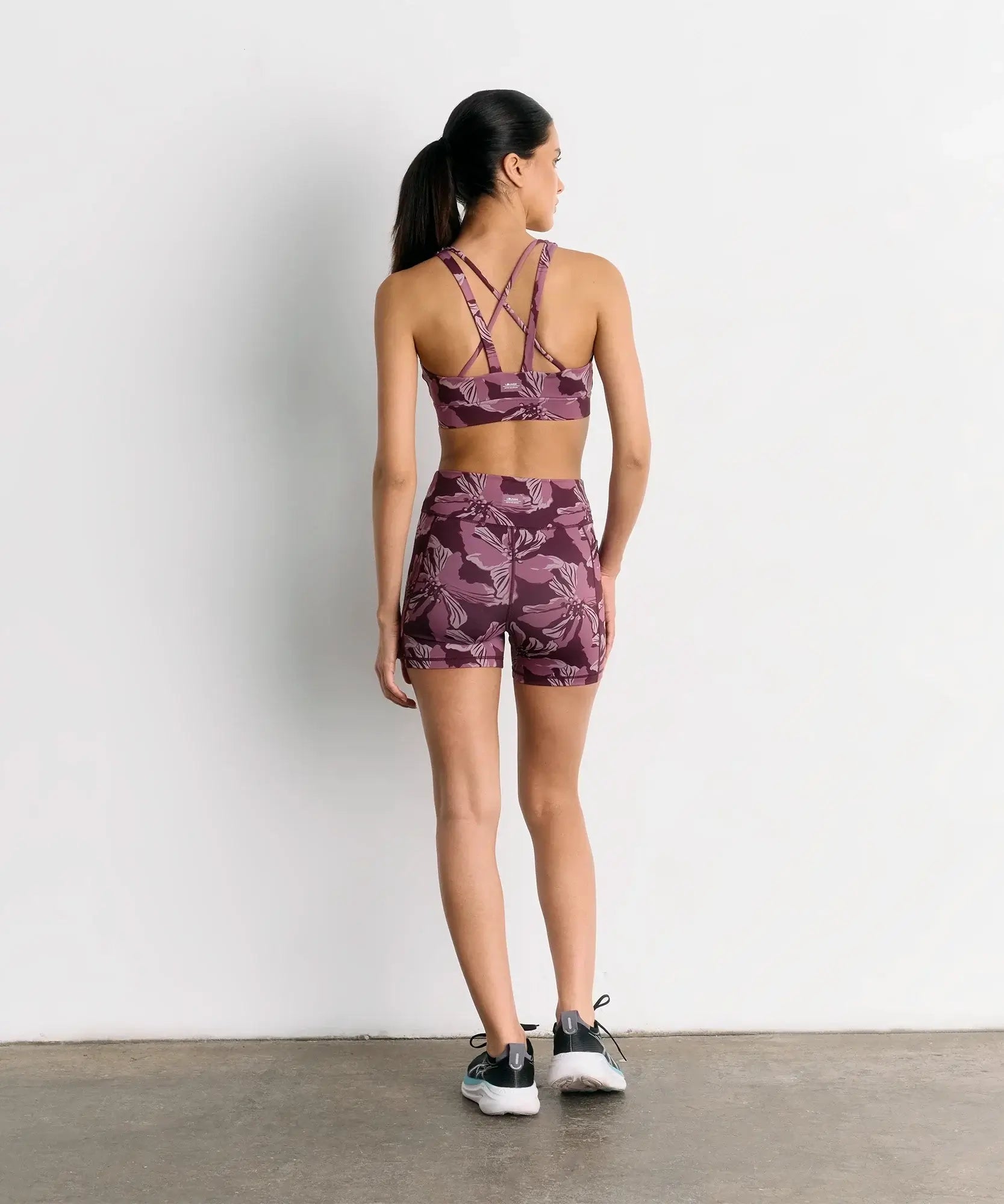 Mujer usando Short Deportivo Biker Flores Active de la marca Lounge, vista trasera con diseño floral.