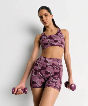 Short Deportivo Biker Flores Active de marca Lounge, modelo en color púrpura con diseño de flores, con pesas en las manos.