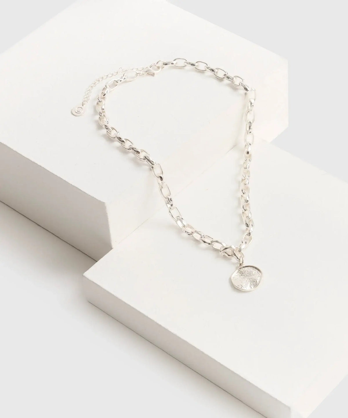 Collar Charm Machacado de marca Lounge, con cadena gruesa y charm redondo machacado sobre fondo blanco.