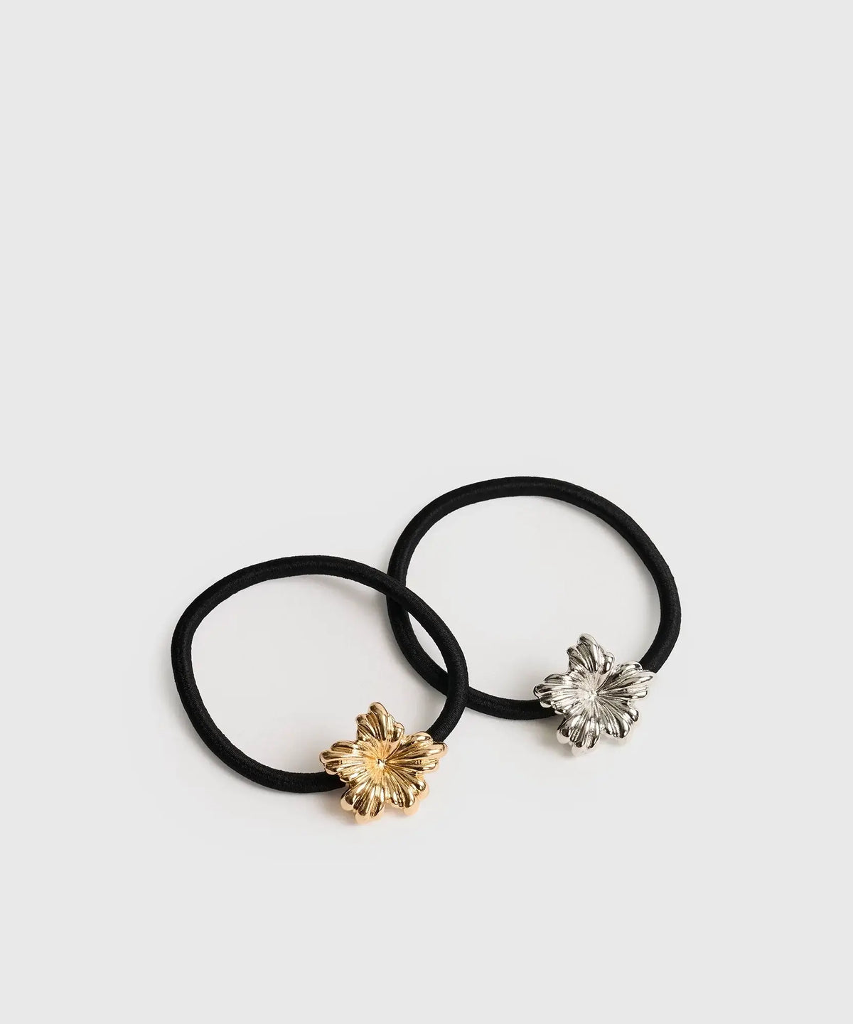 Set Collets Detalle Metal de marca Lounge con dos elásticos negros y detalles de flores metálicas en dorado y plateado.