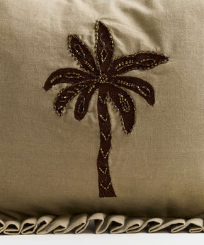 Decorative pillow with brown palm tree embroidery and ruffled edge, perfect for tropical-themed decor.
