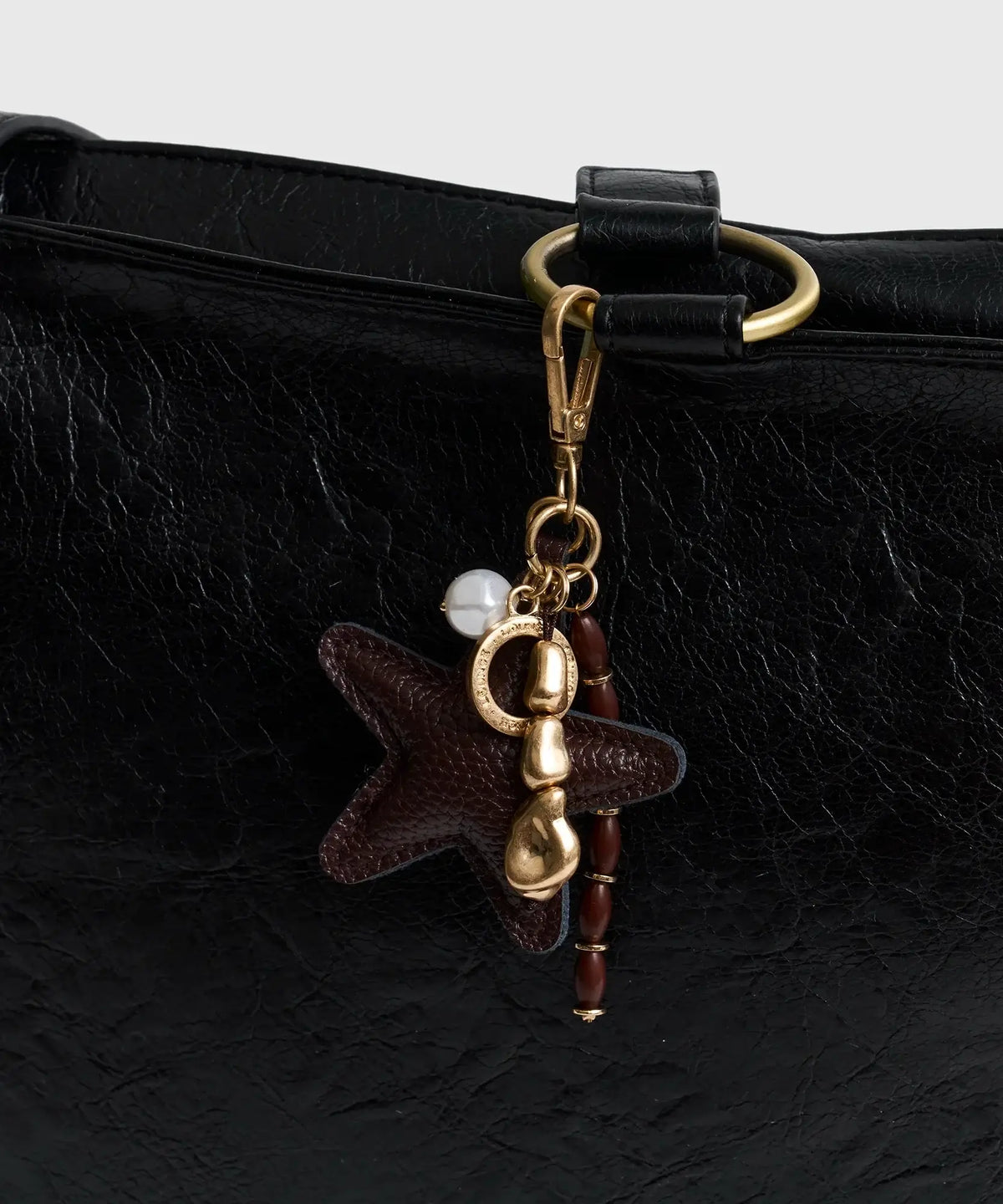 Llavero Estrella de Lounge con charm de estrella y mostacillas en bolso negro.