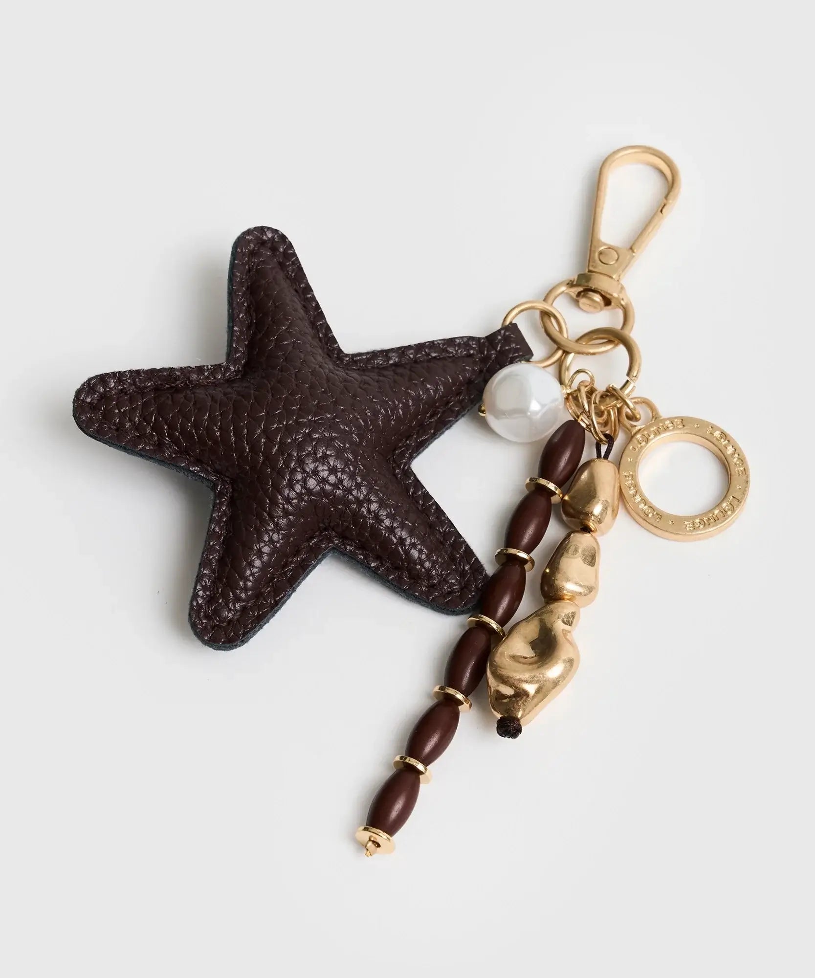 Llavero Estrella de Lounge con charm de estrella y mostacillas en tonos marrón y dorado.