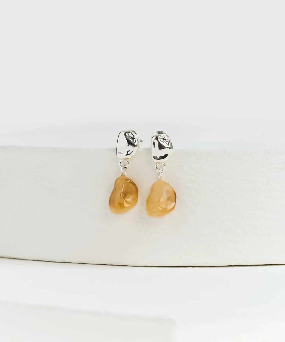 Aros Mini Piedra de la marca Lounge, con mini piedra colgante color ámbar en diseño elegante.