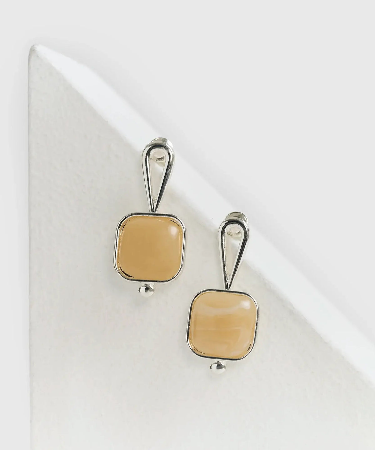 Aros Cuadrados con piedra de Lounge, elegantes aretes cuadrados en tono beige.