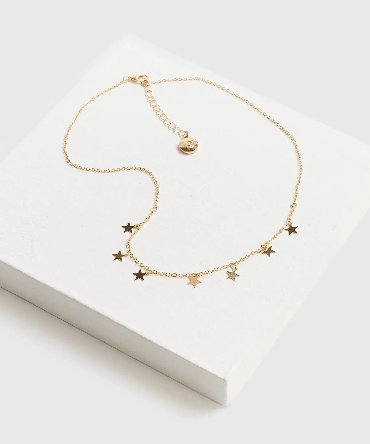 Collar Estrellas Mini de marca Lounge, delicada cadena dorada con mini estrellas, sobre fondo blanco.