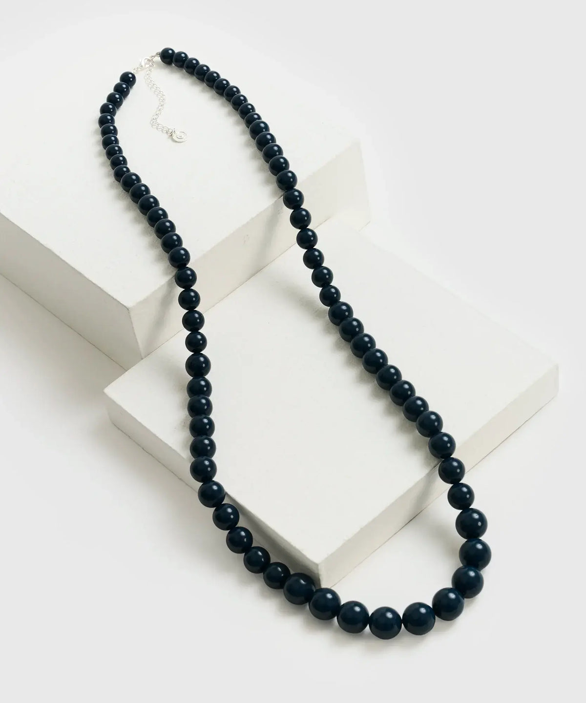 Collar Extra Largo de Lounge, con piedras de diferentes tamaños en tonos oscuros, sobre fondo blanco.