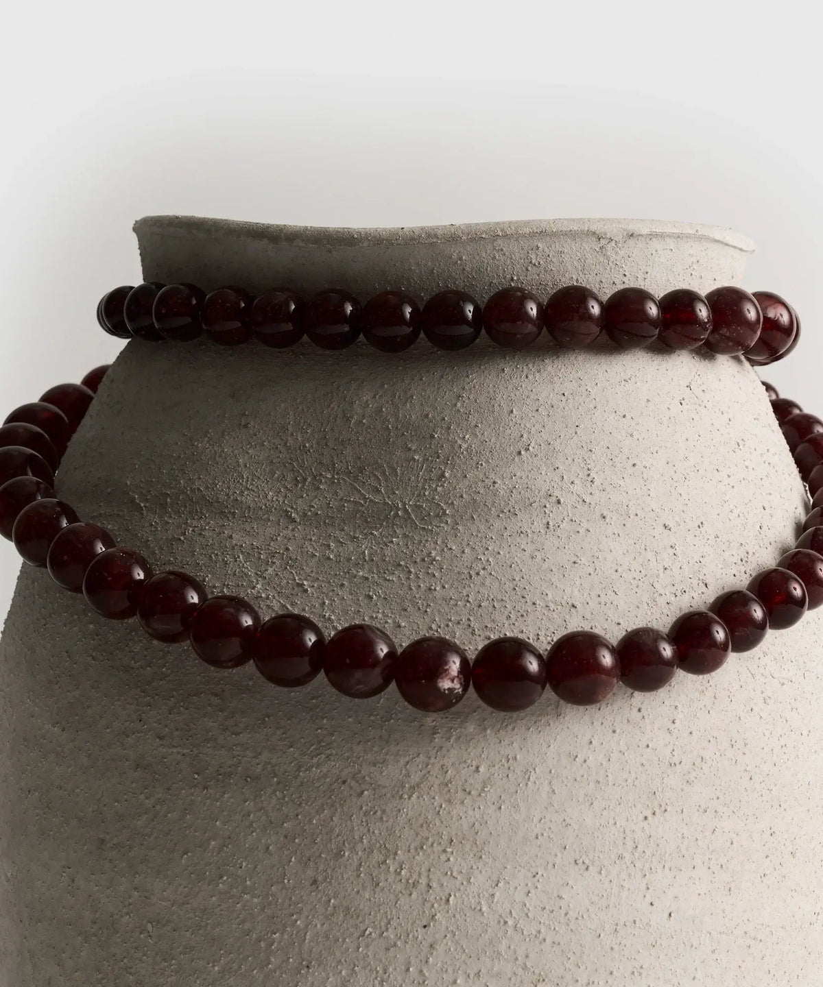Collar Extra Largo de Lounge con piedras de diferentes tamaños sobre una maceta de cerámica.