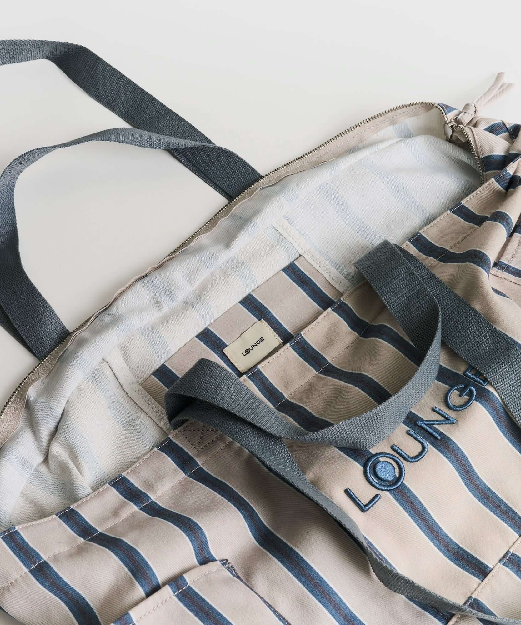 Bolso Playero Antiarena de Lounge, diseñado con múltiples bolsillos y malla antiarena para una mejor organización.