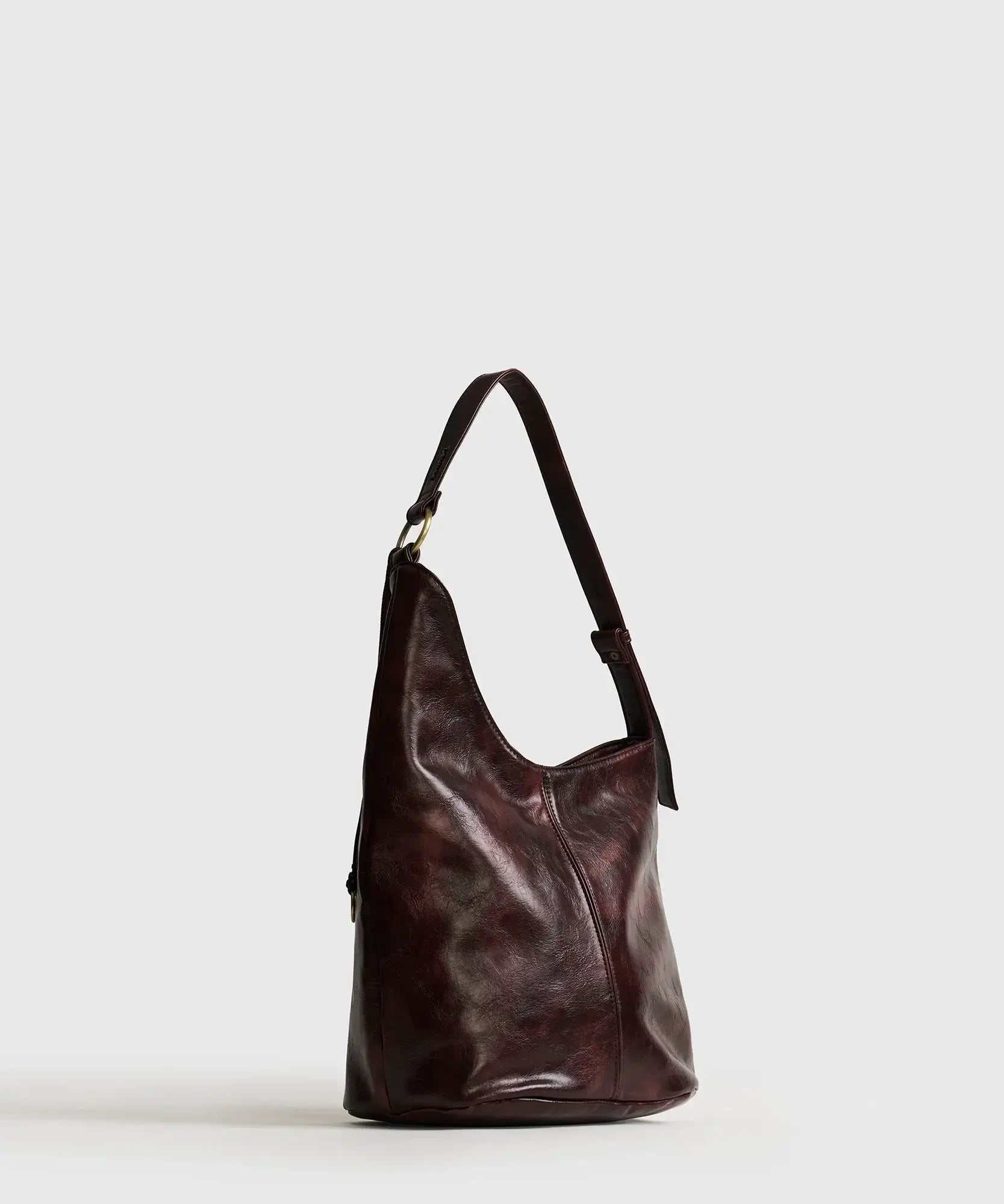 Cartera De Hombro Asimétrica de Lounge, asa ajustable y diseño de argollas en color burdeos.