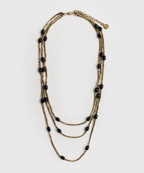 Collar Mostacillas Triple de Lounge, collar largo dorado de tres capas con mostacillas y piedras negras.