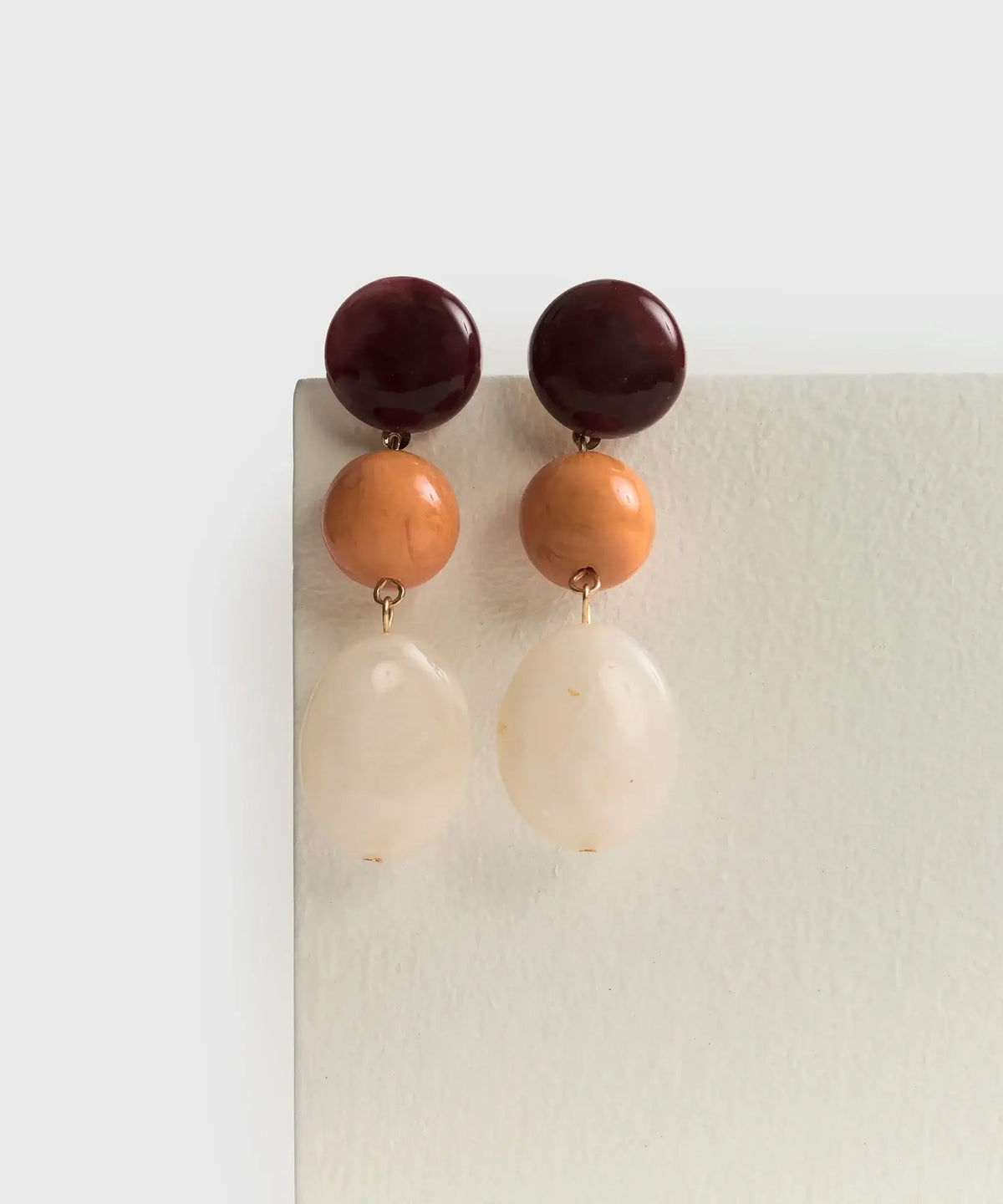 Aros Piedras Colgantes de Lounge, largos con círculos y piedra de resina en tonos cálidos.