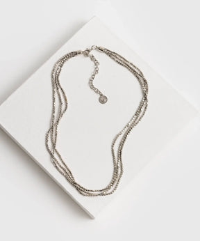 Collar Mostacillas Triple Boho de Lounge, collar de tres capas con mostacillas pequeñas sobre fondo blanco.